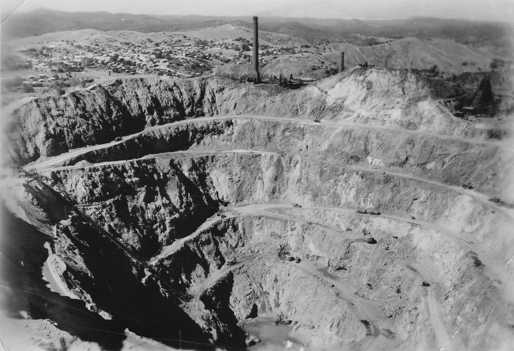 Historical photograph of the Mount Morgan open-cut mine in 1952, showing mine benches, the large excavation and the town beyond.